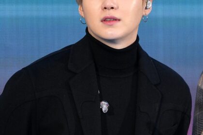 Suga BTS mengenakan setelan hitam saat tampil di depan publik.