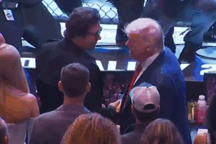 Donald Trump berjabat tangan dengan penonton di acara UFC 316 di tepi oktagon