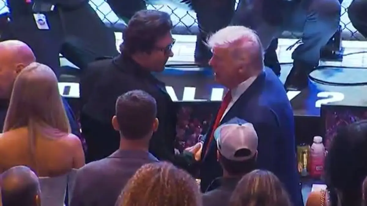Donald Trump berjabat tangan dengan penonton di acara UFC 316 di tepi oktagon