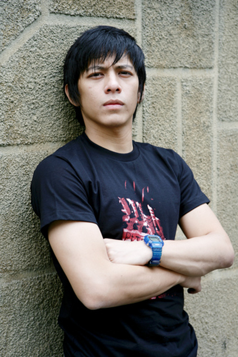 Ariel NOAH mengenakan kaus hitam, berdiri menyandar di tembok.